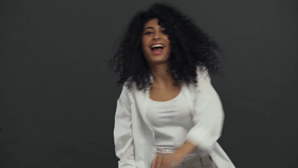 fröhliche bi-rassische Schauspielerin tanzt isoliert auf schwarz - Filmmaterial, Video