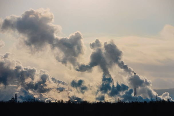 Fabrieksschoorstenen vervuilen de atmosfeer met dichte rook. - Foto, afbeelding