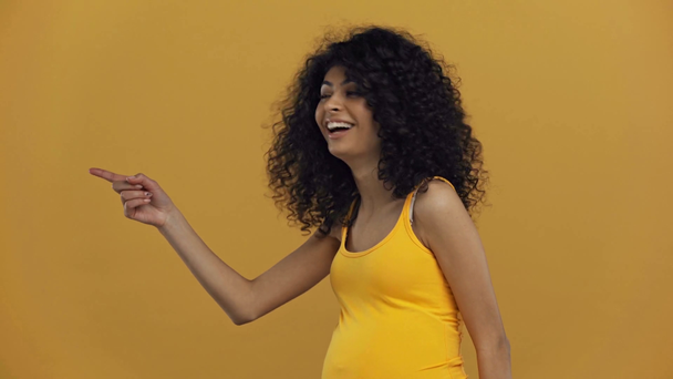 χαρούμενα bi-φυλετική έγκυος γυναίκα δείχνουν με το δάχτυλο απομονώνονται σε σκούρο κίτρινο - Πλάνα, βίντεο