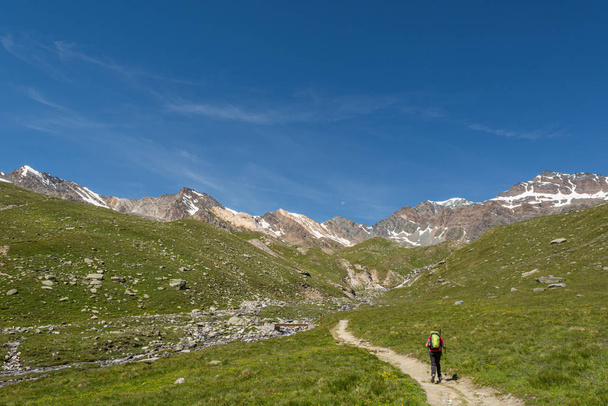 Person hiking through a green mountain valley. - Foto, Imagem