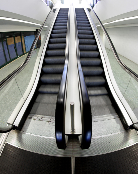 Ampla escada rolante que sobe dentro de um centro de negócios
 - Foto, Imagem