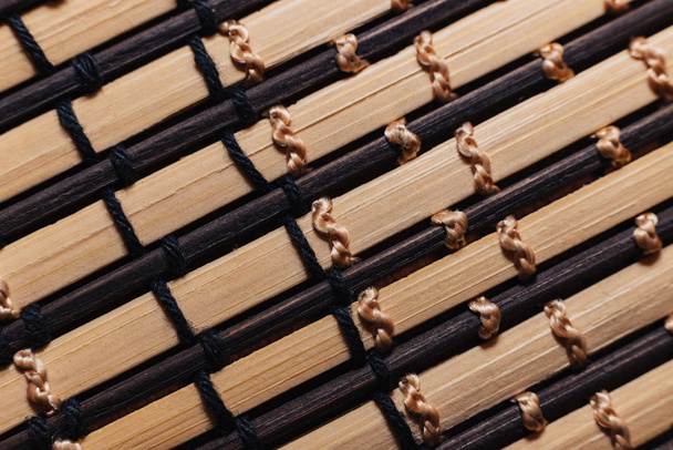 Les bâtons de bambou sont attachés avec des fils blancs et beiges. Tapis de bâtons en bois pour le gros plan de la table. Macro photo de fond abstrait pour papier peint
. - Photo, image