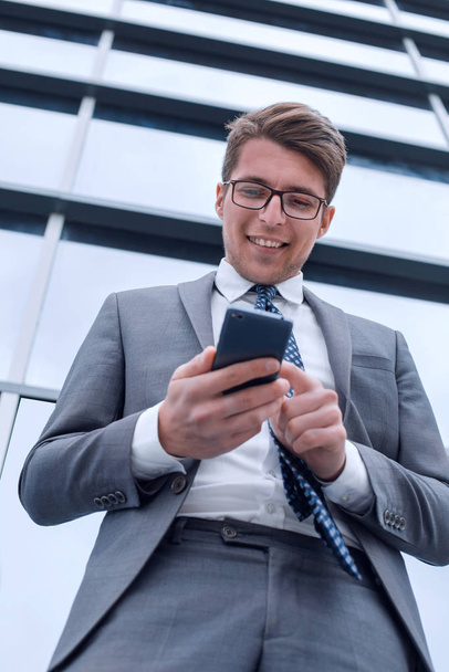 smiling business man reading SMS on his smartphone - Valokuva, kuva