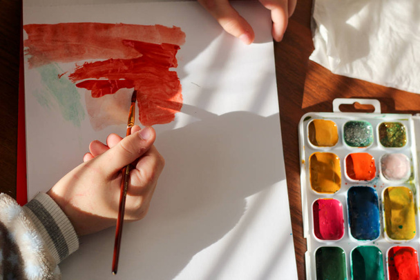 Proces rysowania akwarelą i pędzlem w dłoni dziecka. Rysunek dziecka z akwarelą - Zdjęcie, obraz