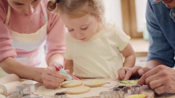 Handheld weergave van het kind het versieren van koekjes onder toeziend oog van ouders. Neergeschoten met Red helium camera in 8k - Video