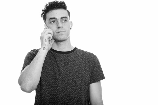Studio shot of young man talking on mobile phone and thinking - Photo, Image
