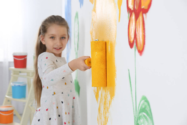 Little child painting wall with roller brush indoors - Фото, изображение