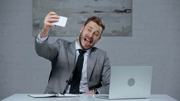 wesoły biznesmen dobrze się bawić podczas robienia selfie w biurze - Materiał filmowy, wideo