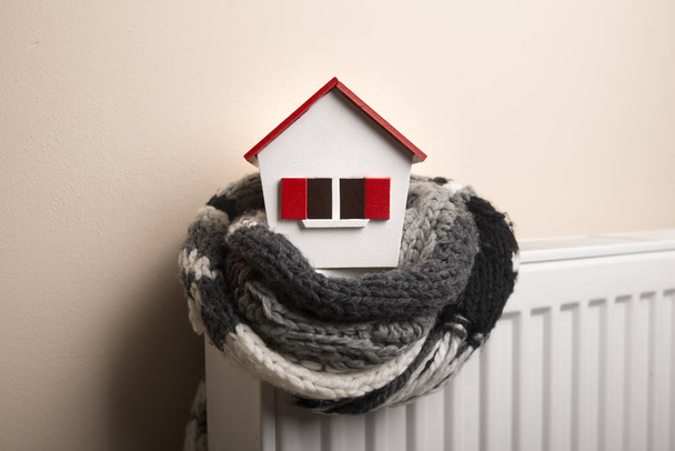 dům v zimě - topný systém koncept a studené zasněžené počasí s modelem domu pletené čepici - Fotografie, Obrázek