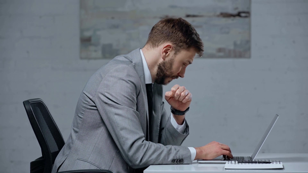 chory biznesmen kaszel podczas pisania na laptopie - Materiał filmowy, wideo