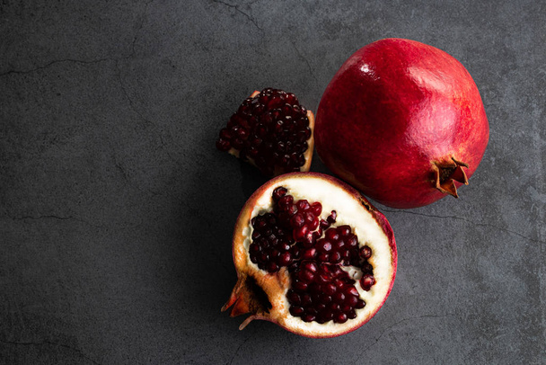 Ripe pomegranate fruits on a dark background, top view with copy - Foto, immagini