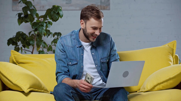 gelukkige gokker die dollarbankbiljetten vasthoudt terwijl hij online weddenschappen doet - Video