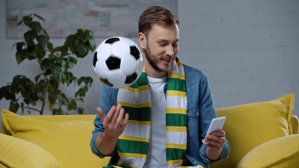 hombre sonriente jugando pelota de fútbol mientras que hace apuestas en línea
  - Metraje, vídeo