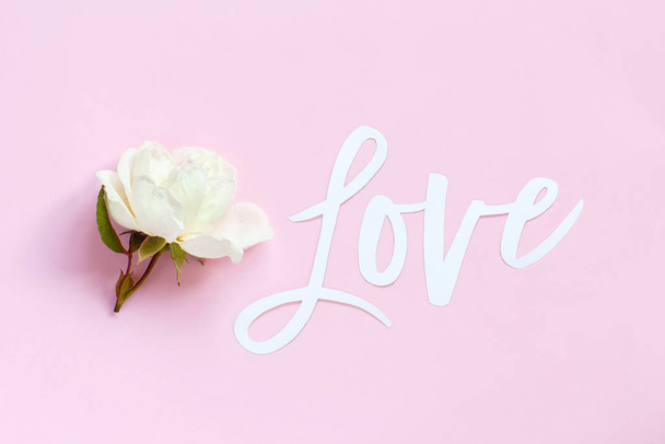 Crème roos en tekst Liefde op een licht roze achtergrond - Foto, afbeelding