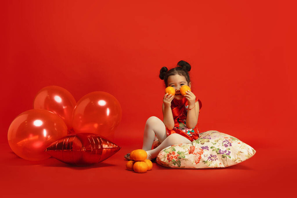 Happy Chinese New Year. Asian little girl portrait isolated on red background - Foto, Imagen