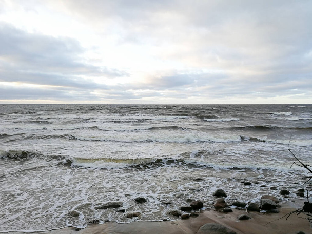 Naturaleza severa de diciembre en la orilla del mar Báltico. Clima letón en invierno. Costa del mar con pequeñas rocas, hierba vieja y olas venideras
.   - Foto, imagen