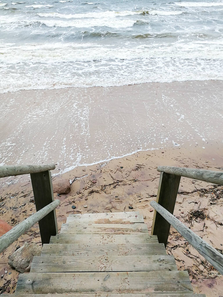 浸水したビーチの海岸につながる木製の階段。12月の嵐の間にバルト海と天気。北の国と沿岸の自然の美しさ.   - 写真・画像