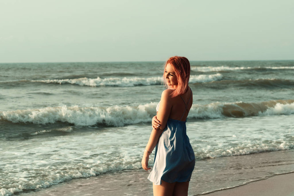 Nainen mekko vaaleanpunaiset hiukset poseeraa meren taustalla - Valokuva, kuva