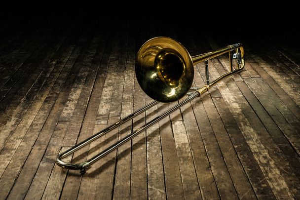 trombone instrument en laiton doré repose sur une scène en bois brun
 - Photo, image