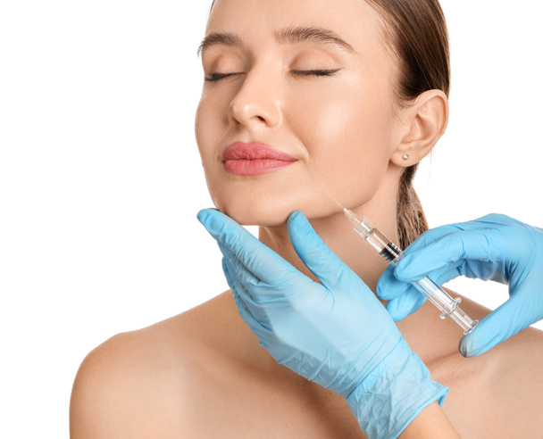Young woman receiving filler injection against white background - Foto, Imagen