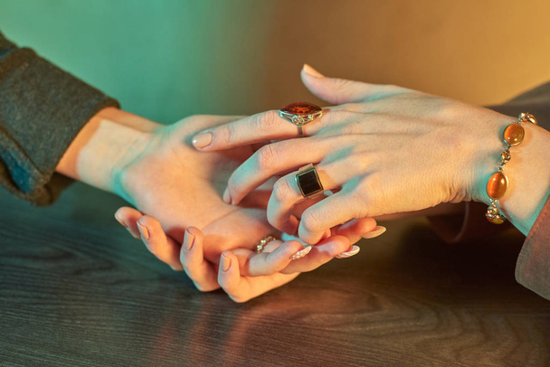 Μάγισσα λέει την τύχη σε μια άλλη γυναίκα, χέρια γεμάτα κοσμήματα - Φωτογραφία, εικόνα