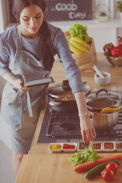 Woman baking at home following recipe on a tablet - Valokuva, kuva