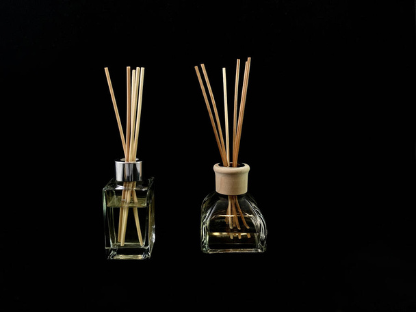 Air freshener on a black background. Incense sticks in a container with perfume. Aromatherapy canes in a glass bottle with oil - Foto, Imagem