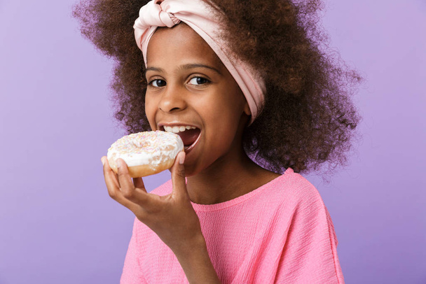 Optimistic young african girl eat donut. - Foto, Imagem