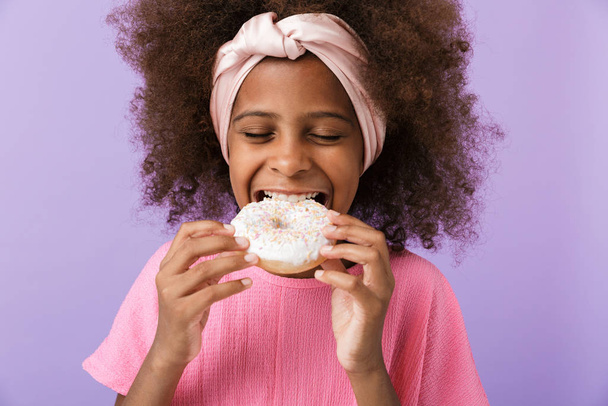 Optimistic young african girl eat donut. - Foto, immagini