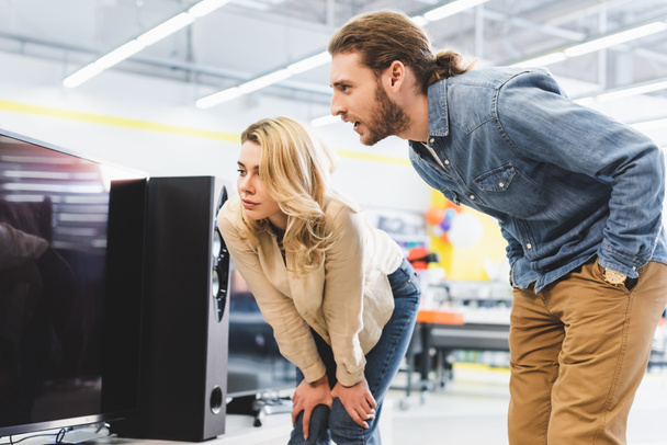 boyfriend and girlfriend looking at new tv in home appliance store  - Foto, imagen