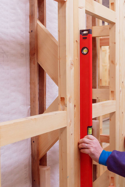 フレームハウスの木造建築物の建設の品質管理。設置構造物の垂直偏差の測定. - 写真・画像