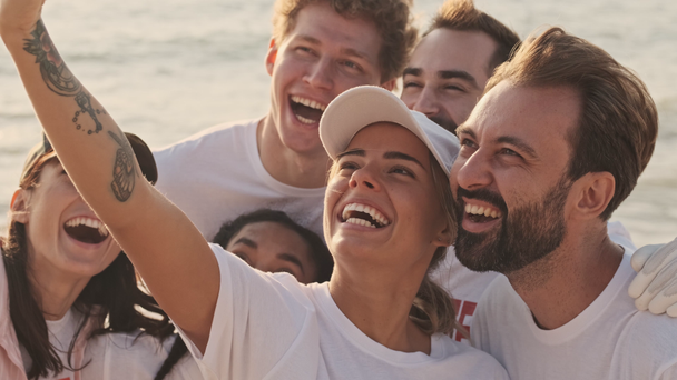 Des bénévoles écologiques souriants et positifs prennent un selfie tout en nettoyant la plage du plastique au bord de la mer
 - Séquence, vidéo