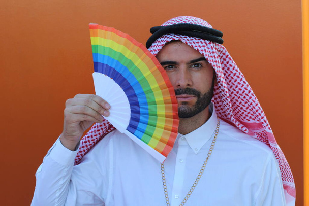 Nahaufnahme Porträt eines hübschen jungen arabischen Mannes mit einem handgehaltenen lgbt-Fan auf der Straße - Foto, Bild