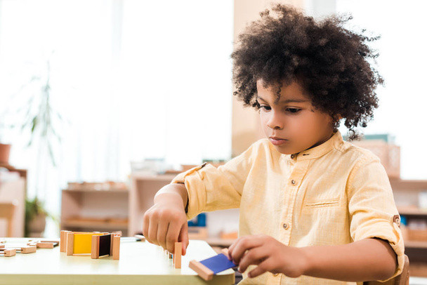 Valikoiva painopiste afrikkalainen amerikkalainen lapsi pelin pöydässä Montessori luokassa
 - Valokuva, kuva