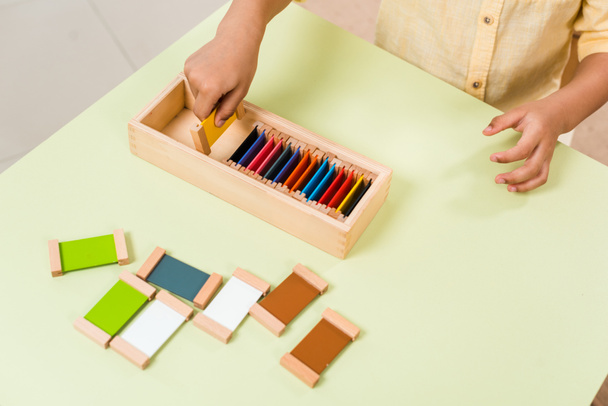 Vue recadrée d'un enfant jouant à un jeu éducatif avec des planches colorées à table à l'école montessori
 - Photo, image