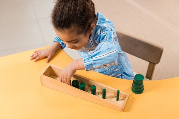 Vue aérienne d'un enfant afro-américain jouant à un jeu en bois à table à l'école montessori
 - Photo, image
