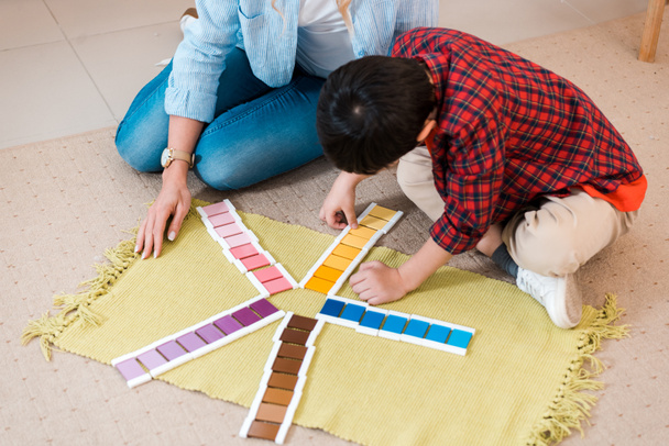 Vista de alto ângulo de professor e criança jogando jogo colorido no chão na escola montessori
 - Foto, Imagem