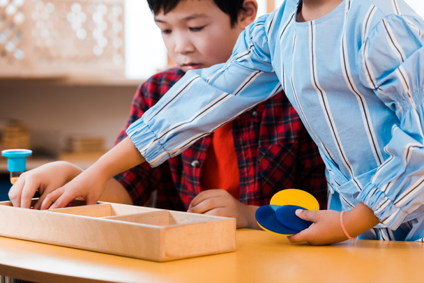 Selectieve focus van kinderen met zandloper en educatief spel aan tafel in Montessori school - Foto, afbeelding