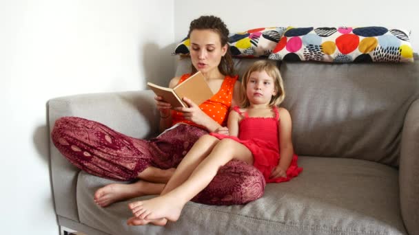 Mom reads a book to her daughter - Materiał filmowy, wideo