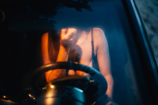 Young woman puts on makeup inside a car at sunset - Photo, Image