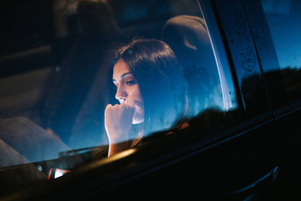 Mujer joven dentro de un coche usando su teléfono inteligente - Foto, Imagen