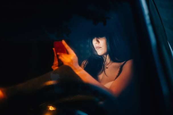Arabadaki genç kadın akıllı telefonunu kullanıyor. - Fotoğraf, Görsel