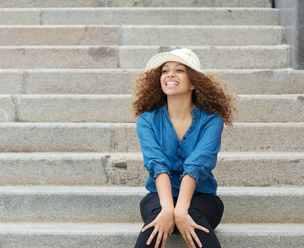 jonge vrouw dragen witte hoed en zitten op de trap - Foto, afbeelding