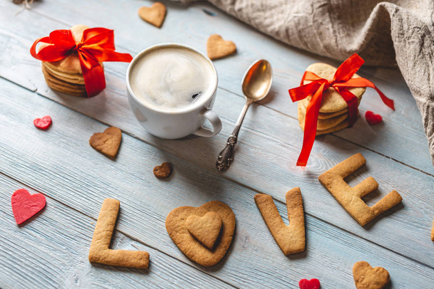 Filiżanka kawy i wiadomość od słodkiego ciasteczka w postaci słowa miłość. Romantyczny prezent Walentynki - Zdjęcie, obraz
