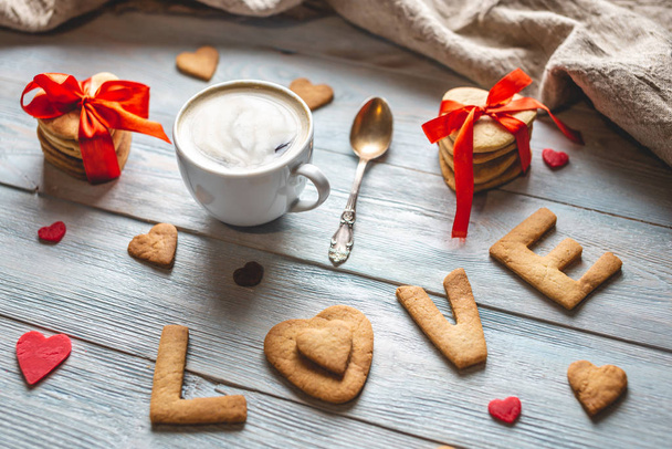 Cup of coffee and a message from a sweet cookie in the form of the word love. Romantic Valentine's day gift - Fotografie, Obrázek