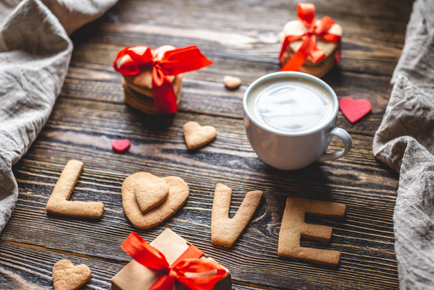 Cup of coffee and a message from a sweet cookie in the form of the word love. Romantic Valentine's day gift - Valokuva, kuva