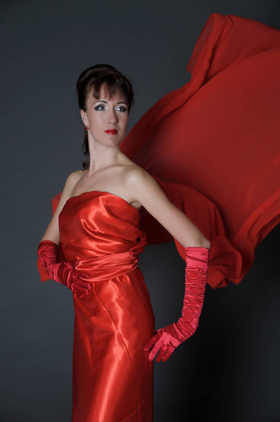 brunette in a red dress on a gray background in the studio and f - Foto, Imagen