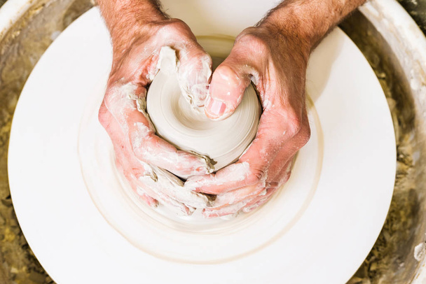 Potter making clay bowl or vase ceramics on the potter's wheel. Creating pottery art and handicraft modelling creation. Hands detail. - 写真・画像