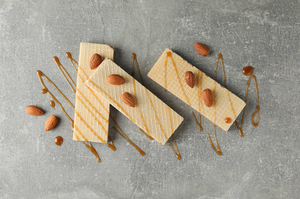 Wafers, caramel topping and almond on grey background, top view - Zdjęcie, obraz