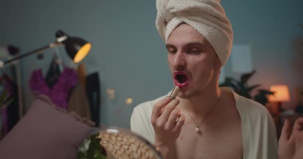 Close up of man travesty diva sitting, putting pink lipstick and getting ready for show. Young man transvestite and looking in mirror while putting on make up and moving head. - Кадри, відео